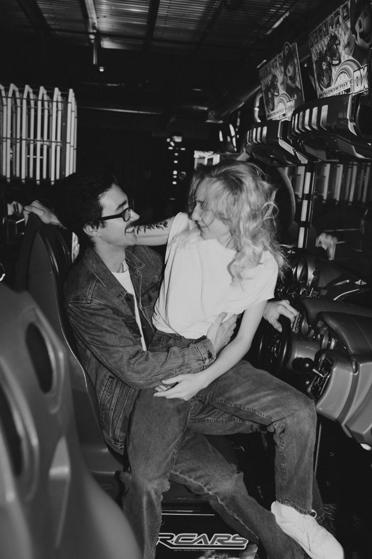 a man and woman sitting on the back of a motorcycle in black and white photo