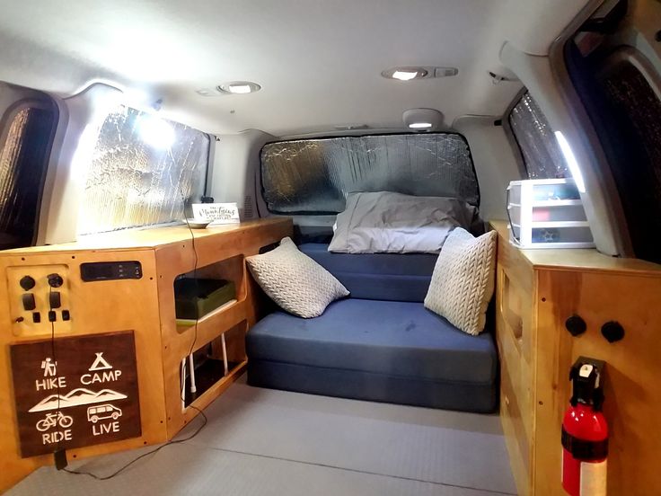 an inside view of a camper van with bed and pillows on the couches