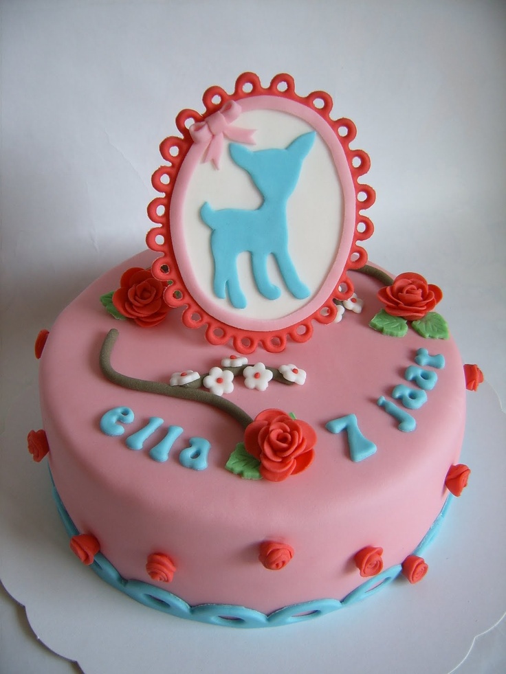 a pink cake with blue frosting and flowers on it's side is shown