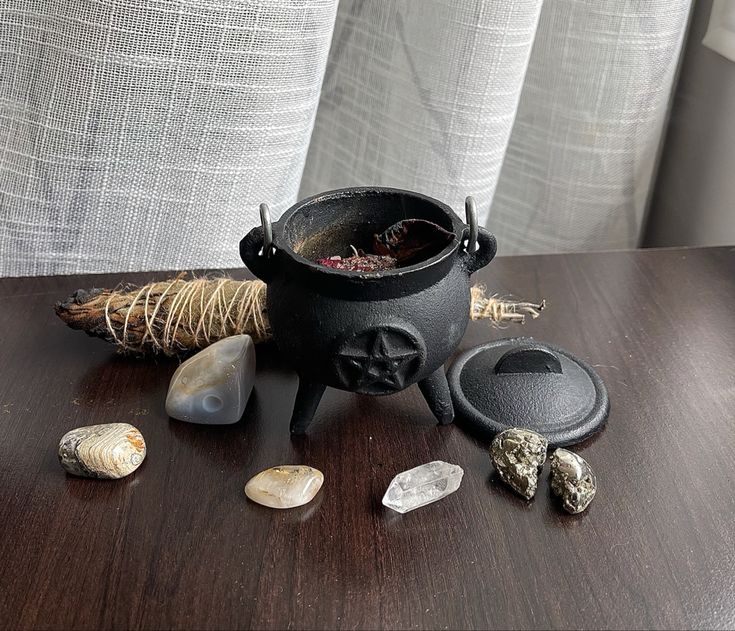 a black pot sitting on top of a wooden table next to rocks and other items