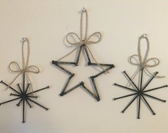 three ornaments are hanging on the wall with twine and ribbons tied around them to create a star ornament