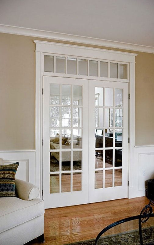 a living room with white furniture and french doors