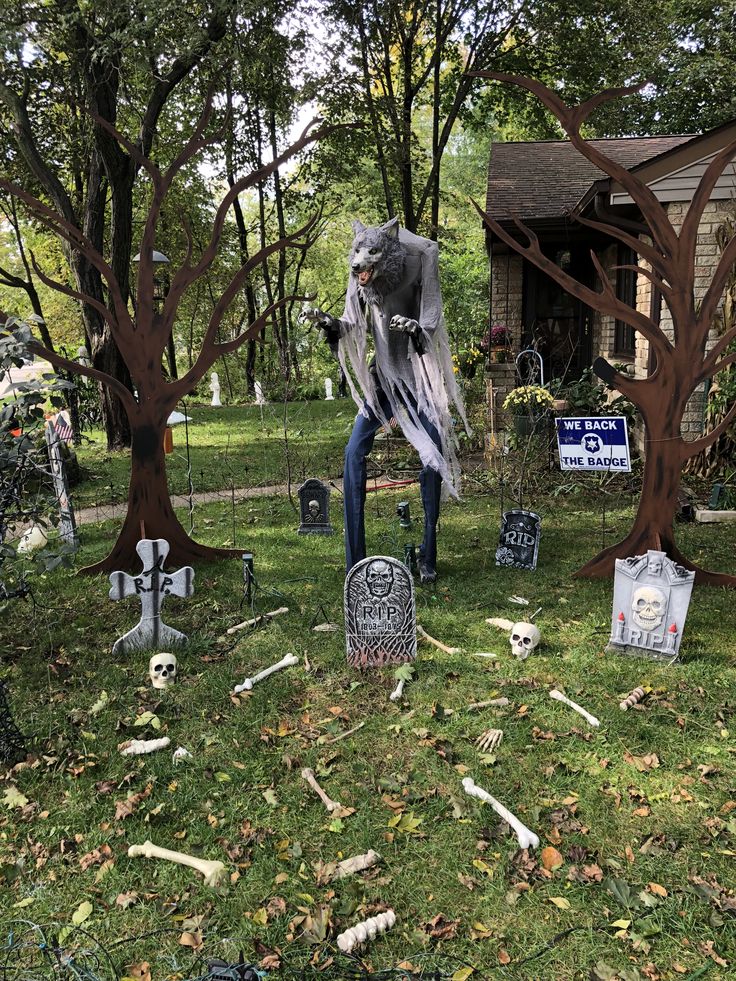 a yard decorated for halloween with skeletons and tombstones in the grass, trees and decorations