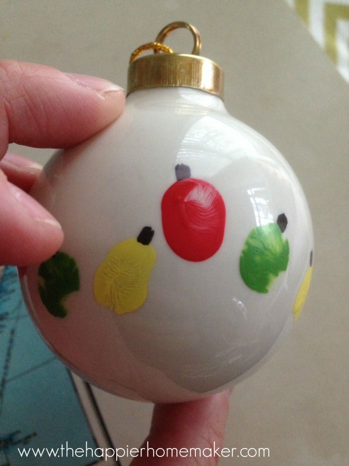 a hand holding a white ornament with colorful designs on it