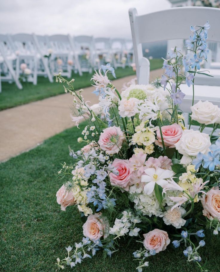 a bouquet of flowers sitting on top of a grass covered field next to chairs and tables