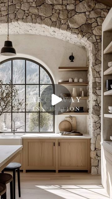 a kitchen with stone walls and an arched window