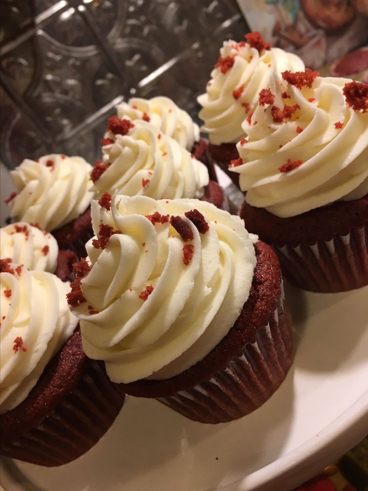 cupcakes with white frosting and red sprinkles on a plate