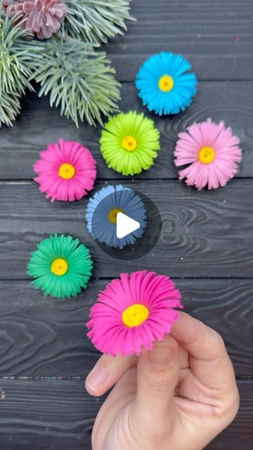 someone is holding up some colorful paper flowers