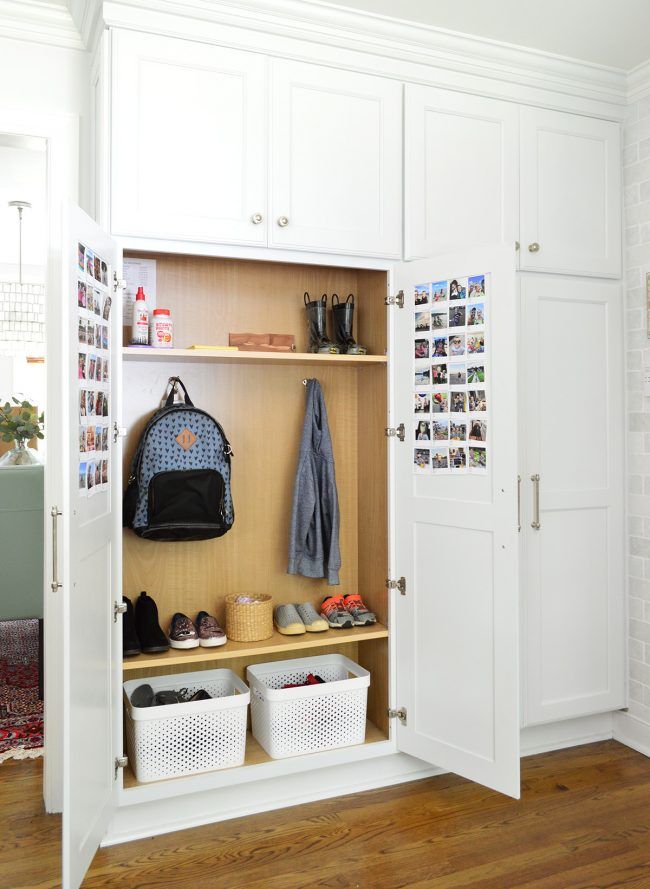 an open white closet with shoes and handbags on it, next to a wooden floor