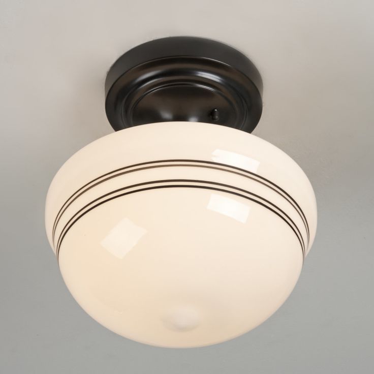 a ceiling light with a white glass shade on it's side and black trim around the rim