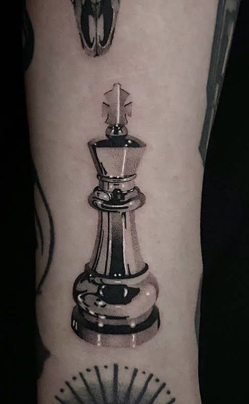 a black and white photo of a chess piece tattoo on the right arm, next to an image of a man's face