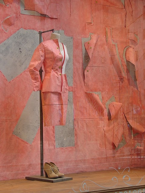 a mannequin's dress on display in front of a pink wall with peeling paint