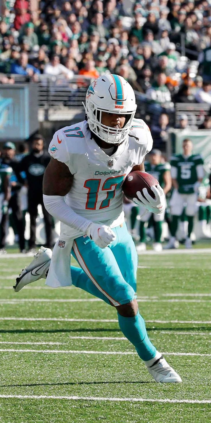 a football player running with the ball in his hand and people watching from the stands