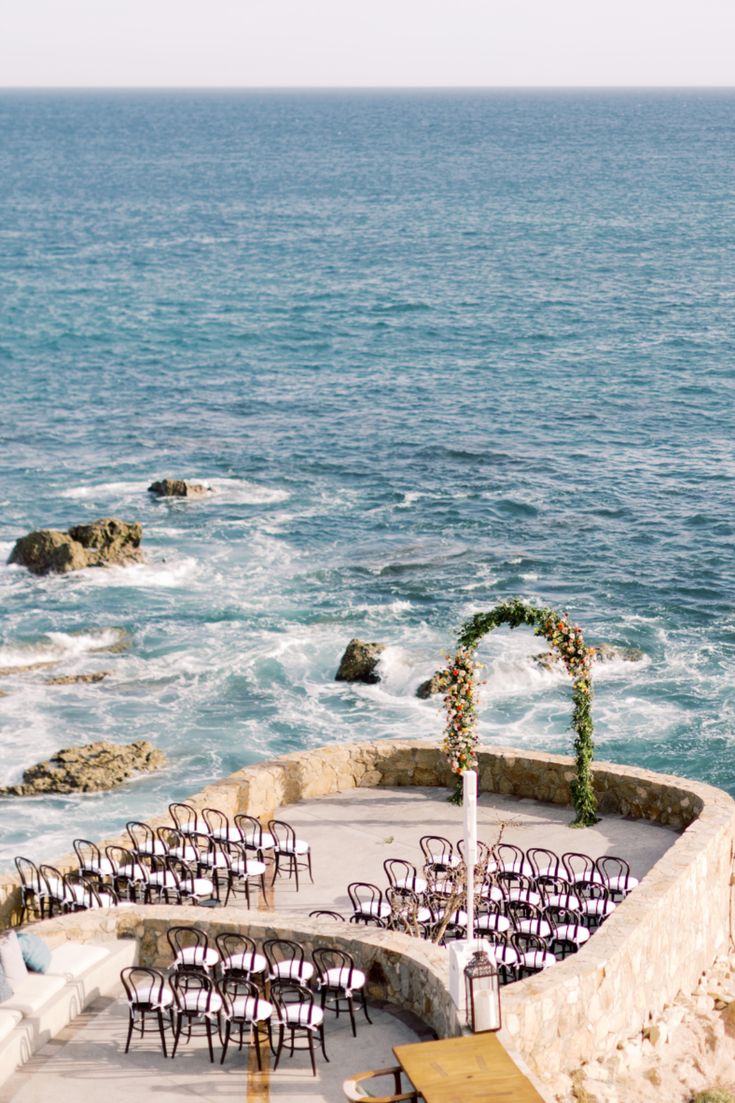 an outdoor seating area with chairs and tables overlooking the ocean