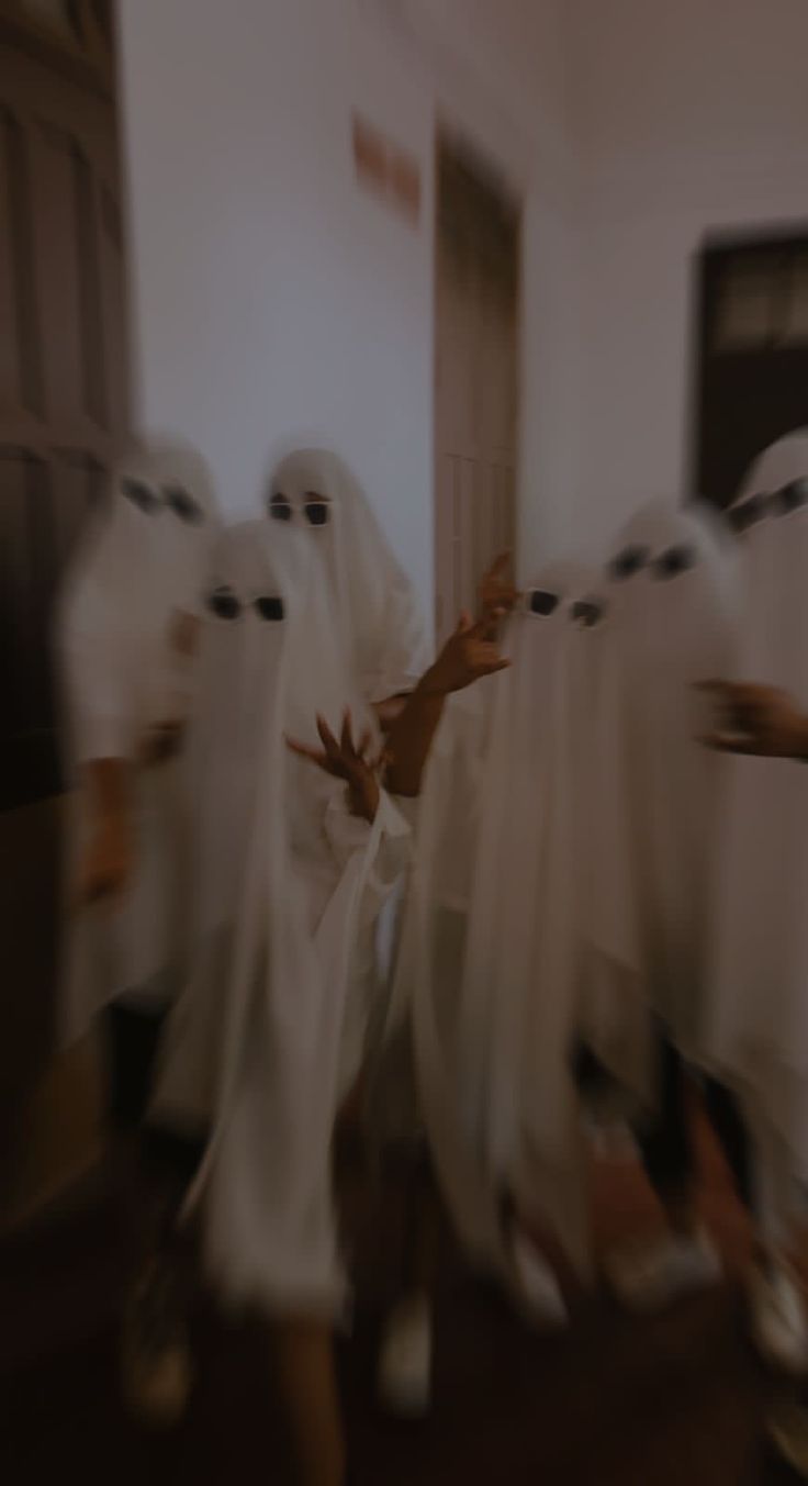 blurry image of people dressed in white robes dancing together with hands out to each other