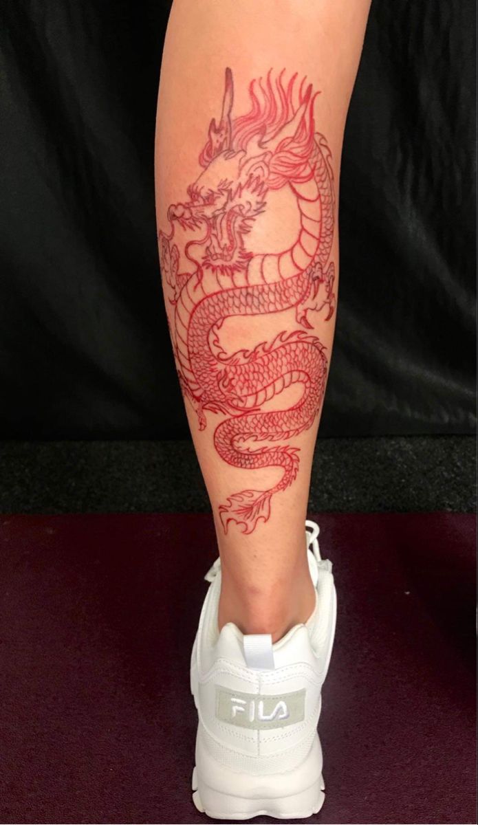 a woman's leg with a dragon tattoo on it, and white tennis shoes