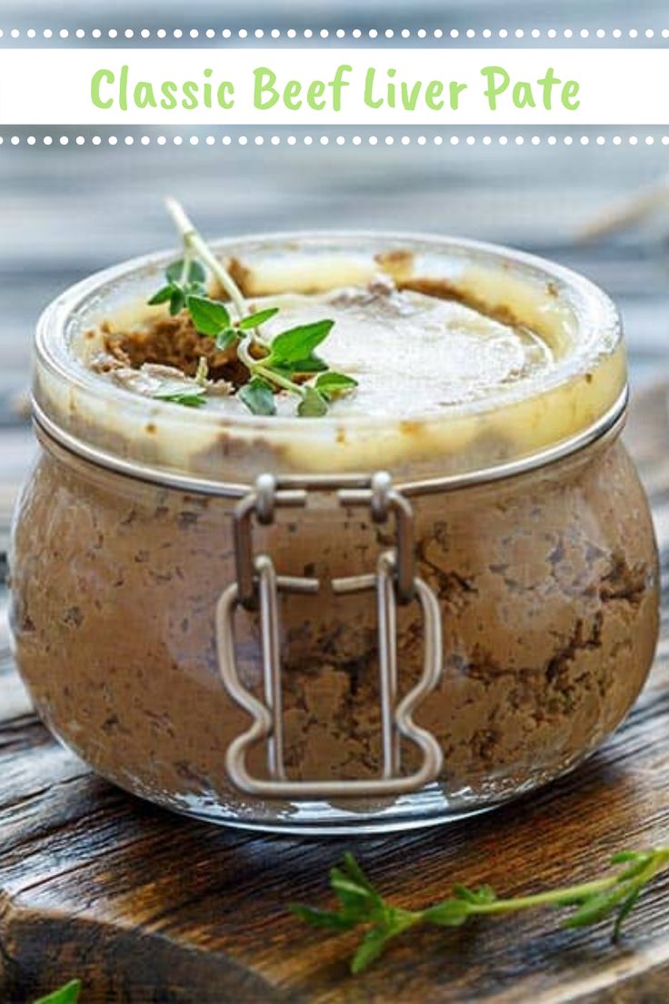 a glass jar filled with food sitting on top of a wooden table next to green leaves