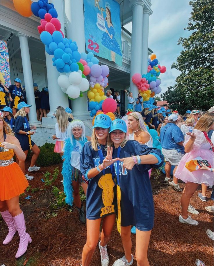 two girls in costumes standing next to each other with balloons and streamers all around them