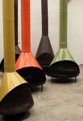 four different colored wood burning stoves sitting on the floor in front of a white wall