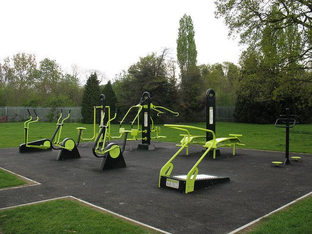 an outdoor gym area with exercise equipment in the middle and grass on the other side