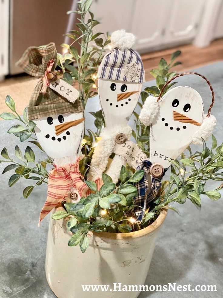 three snowmen are sitting in a potted plant