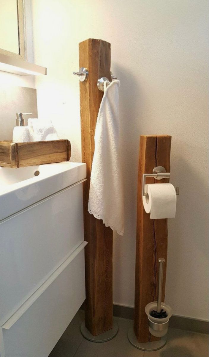 a bathroom with two wooden poles holding toilet paper and a white towel hanging on the wall