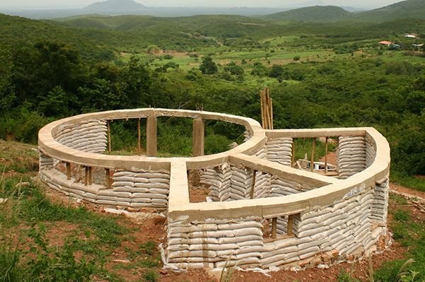 a circular structure made out of sandbags on top of a hill with mountains in the background