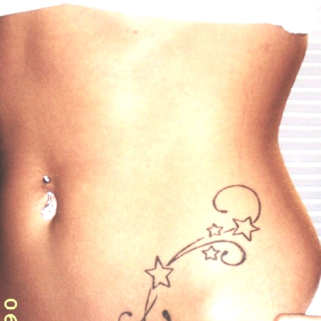 a woman's stomach with an arrow and stars tattoo on her left side belly