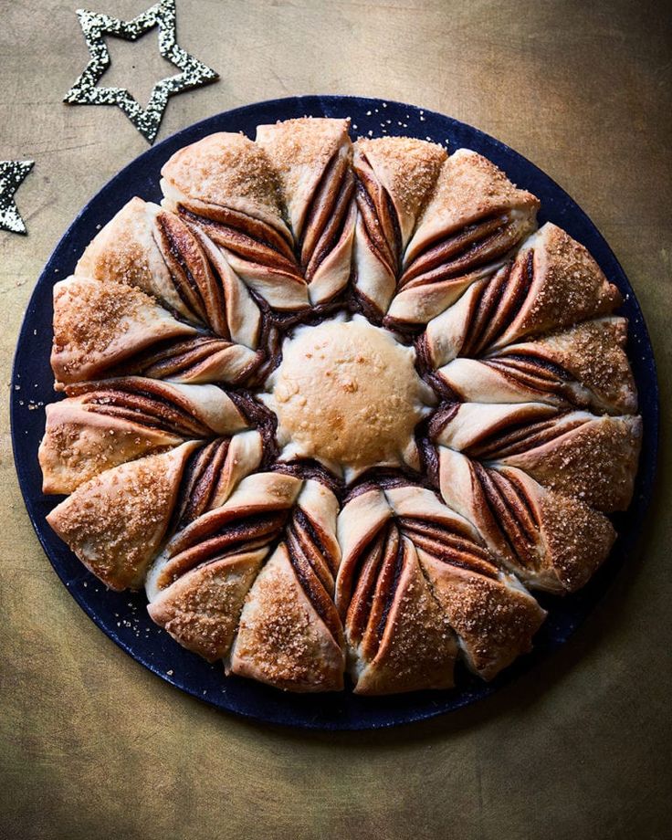 a blue plate topped with a pastry covered in icing and pecans on top of a wooden table