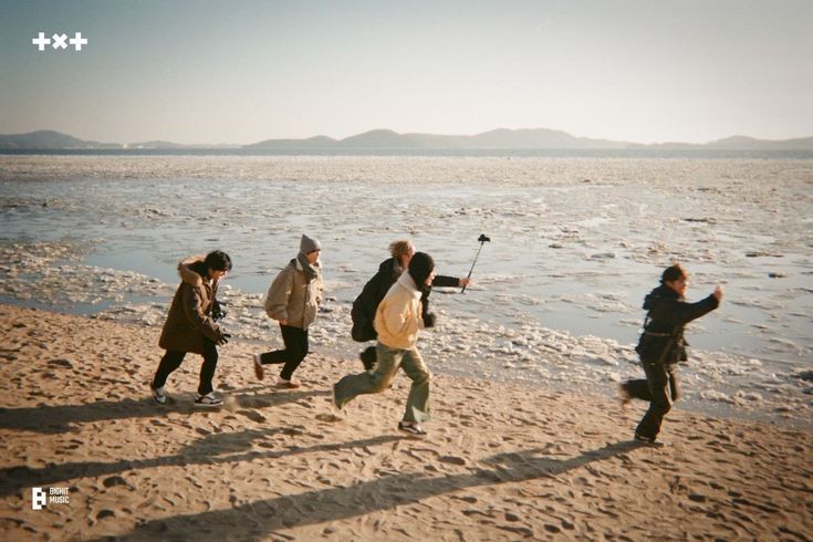 a group of people walking along a beach next to the ocean