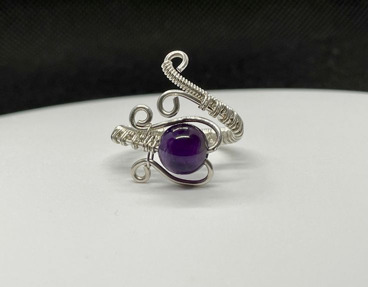 Adjustable Size Sterling Silver wire wrapped Ring with Amethyst. Adjustable from size 7-11. Amethyst is one of the most famous and prominent crystals because of its beautiful coloration as well as its spiritual and literal meaning. The spiritual meaning of Amethyst is groundedness, tranquility, and calm. Band Fits, Sterling Silver Wire Wrap, Spiritual Meaning, Wire Wrapped Rings, Ring Sizes, Wrap Rings, Amethyst Gemstone, 7 11, The Deep