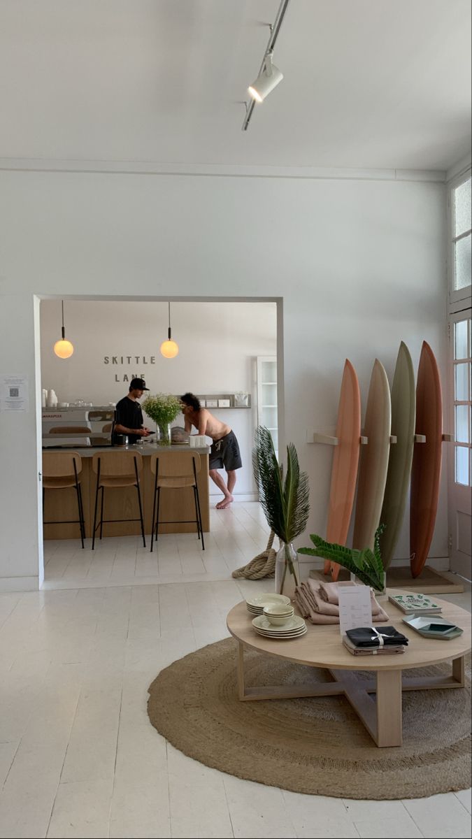 a living room filled with lots of furniture and surfboards on top of a table