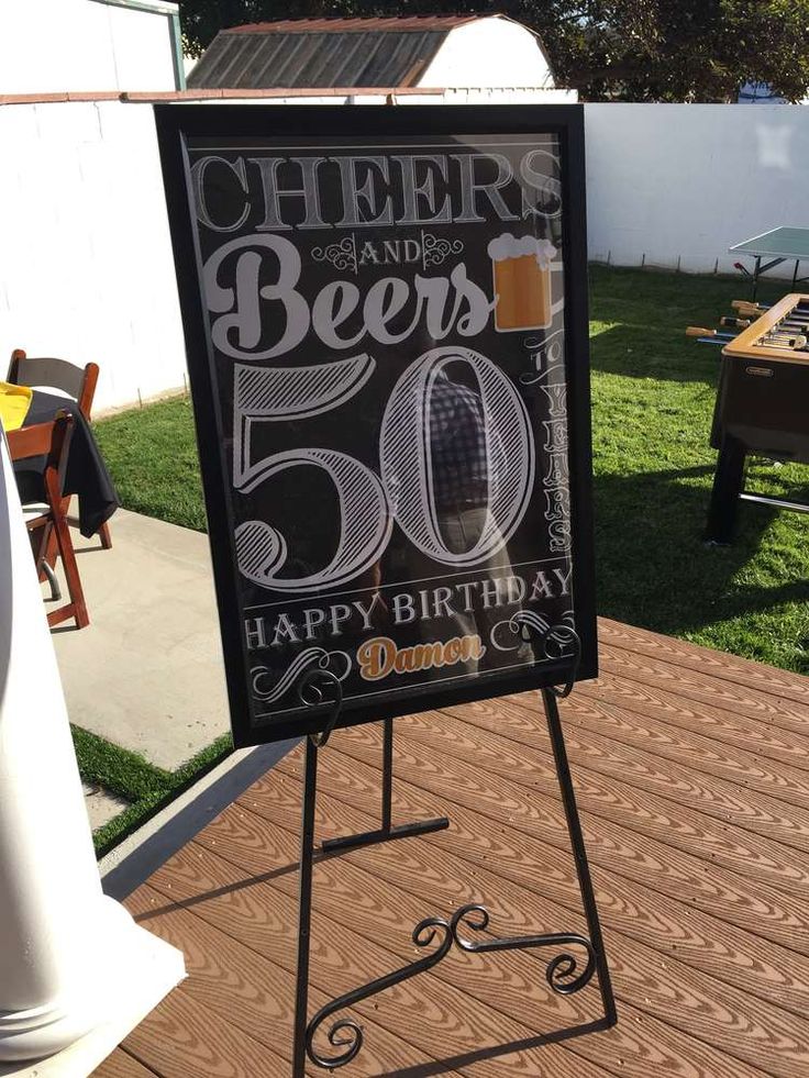 a sign that says cheers and beers on the side of a wooden deck in front of a picnic table