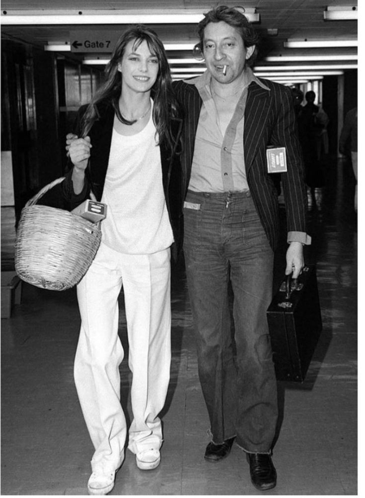 a man and woman are walking through an airport with luggage in their hands, one is holding a basket