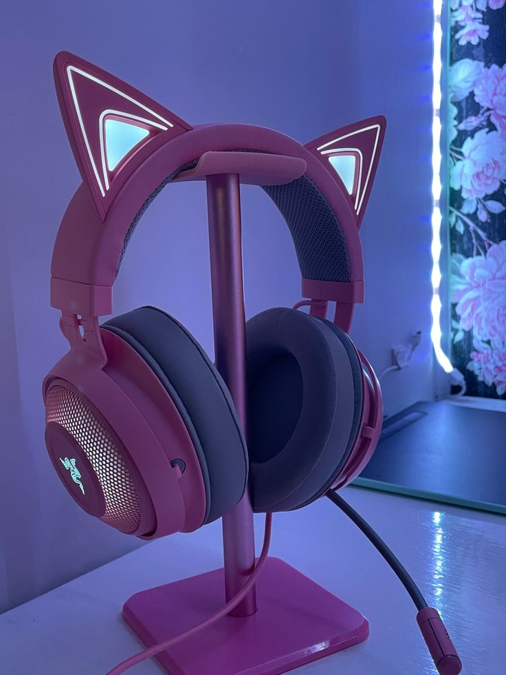 a pair of pink headphones sitting on top of a stand in front of a flowered wall