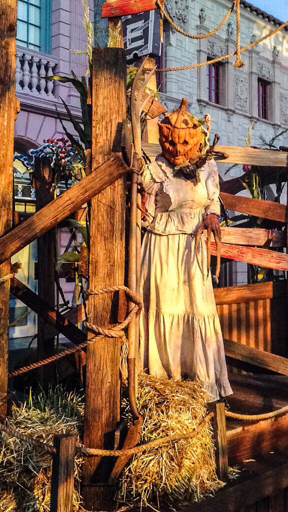 a statue of a woman holding a basket on top of a wooden post in front of a building