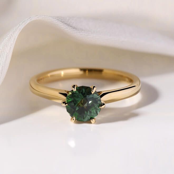 a green ring sitting on top of a white cloth