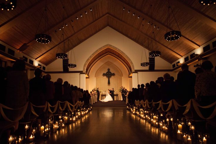 a church filled with lots of candles and people standing in front of the pews