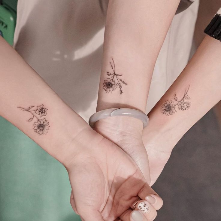 two people holding hands with matching tattoos on their arms and one is holding the other's hand