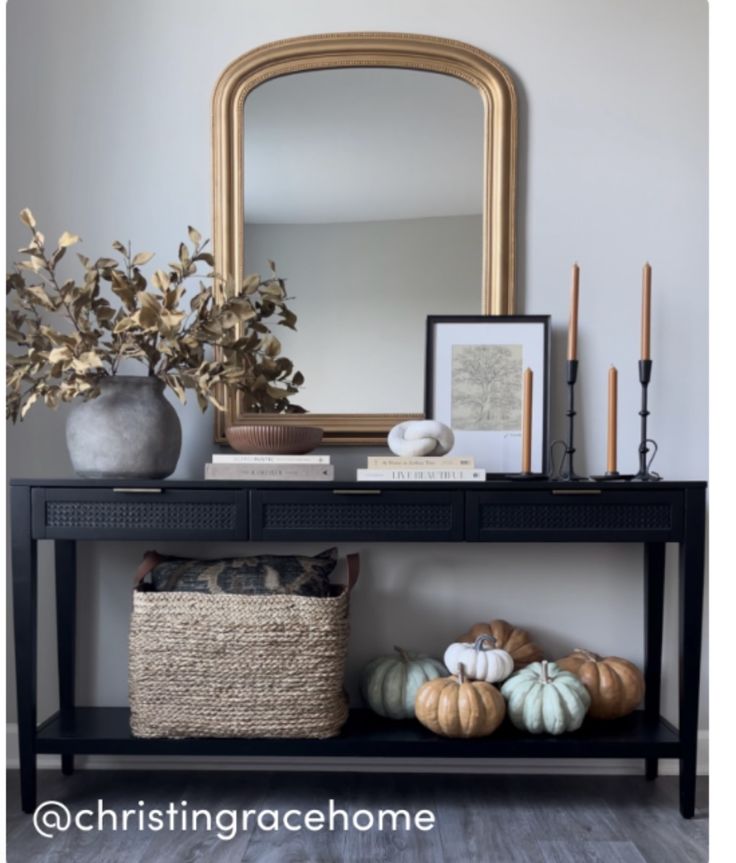 a black table with some pumpkins and a mirror on the wall above it,