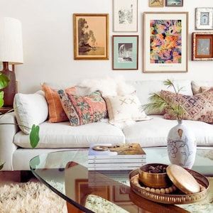 a living room filled with lots of furniture and pictures on the wall above it's glass coffee table