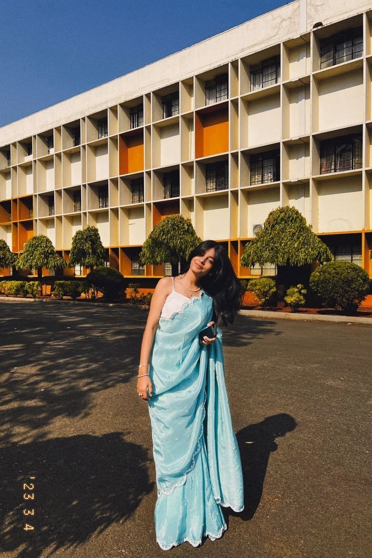 a woman in a blue dress standing in front of an apartment building