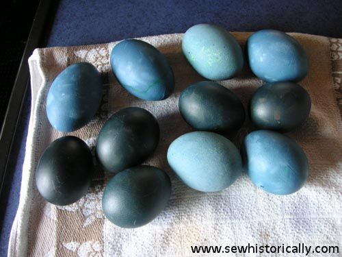 several blue and green eggs on a white towel