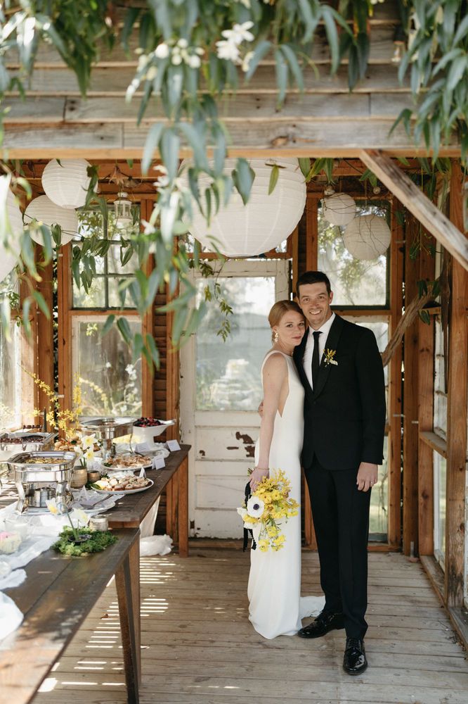 a bride and groom standing in front of a table full of food