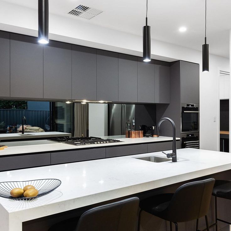 a kitchen with white counter tops and black chairs