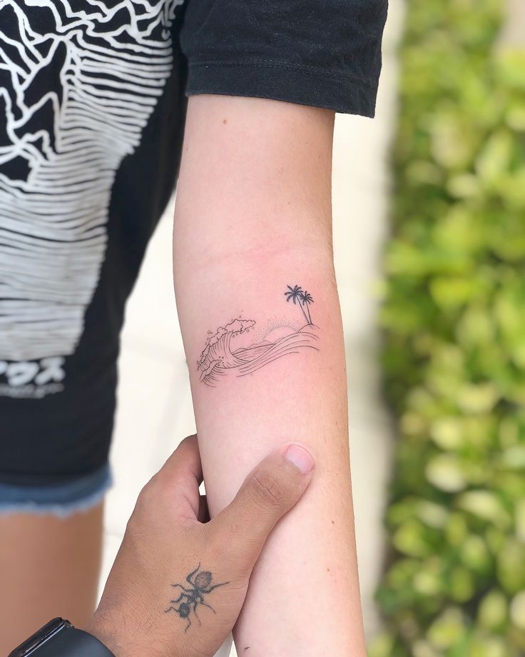 two people holding each other's hands with tattoos on their arms and palm trees in the background