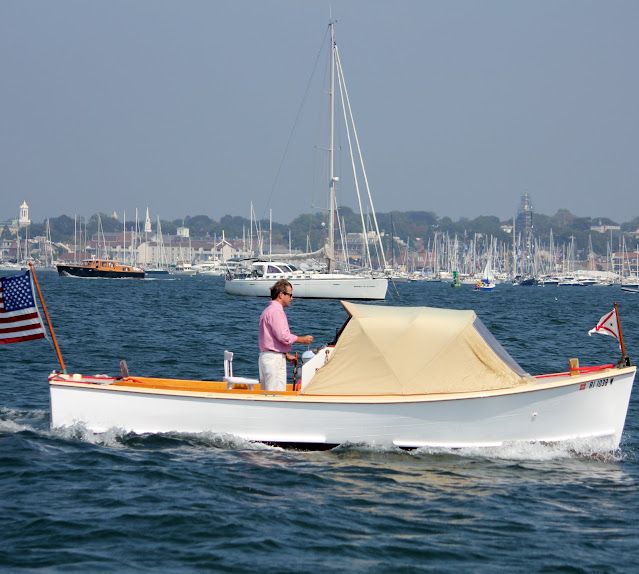 a man on a boat in the water with an american flag flying from it's bow