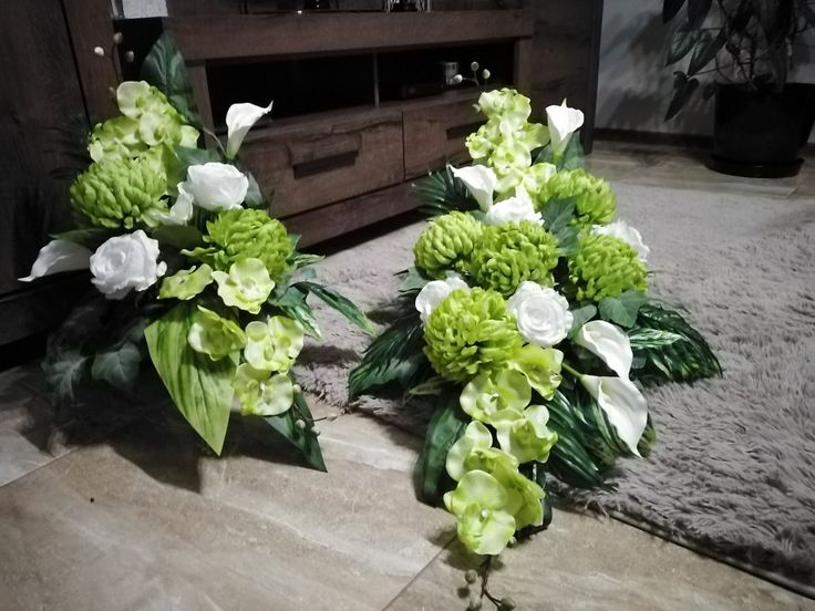 two vases filled with green and white flowers sitting on top of a floor next to a tv