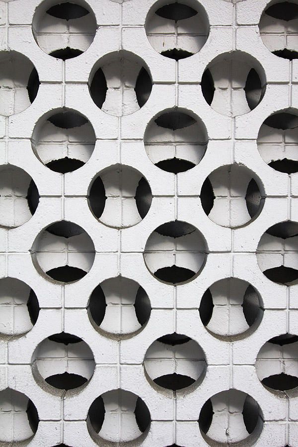 a white wall with holes in the middle and black circles on it's side