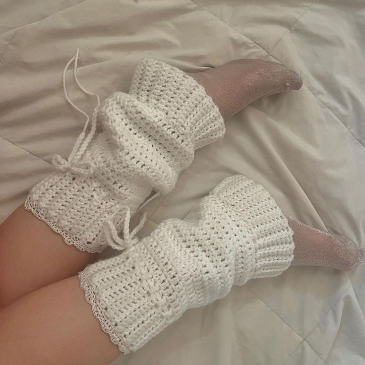 a woman laying on top of a bed wearing white crocheted socks and boots